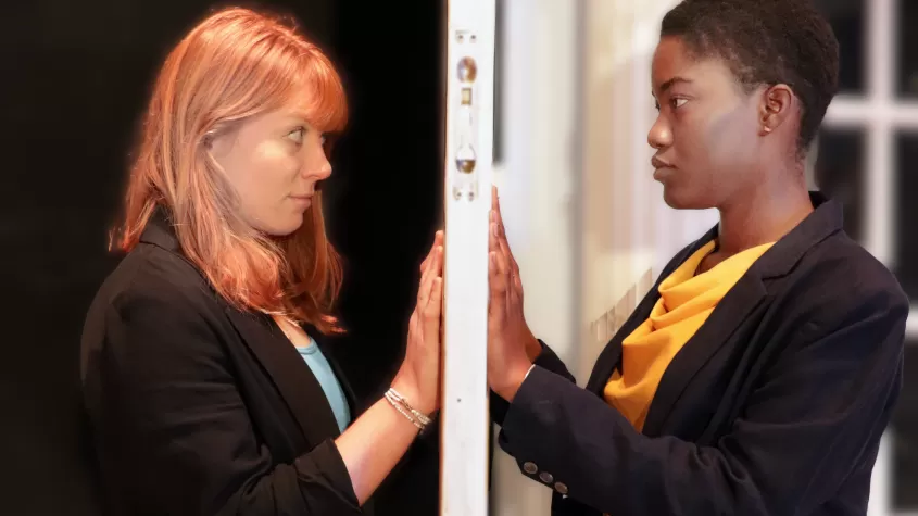 An image of a red headed white woman and a short haired Black woman on opposite sides of a door